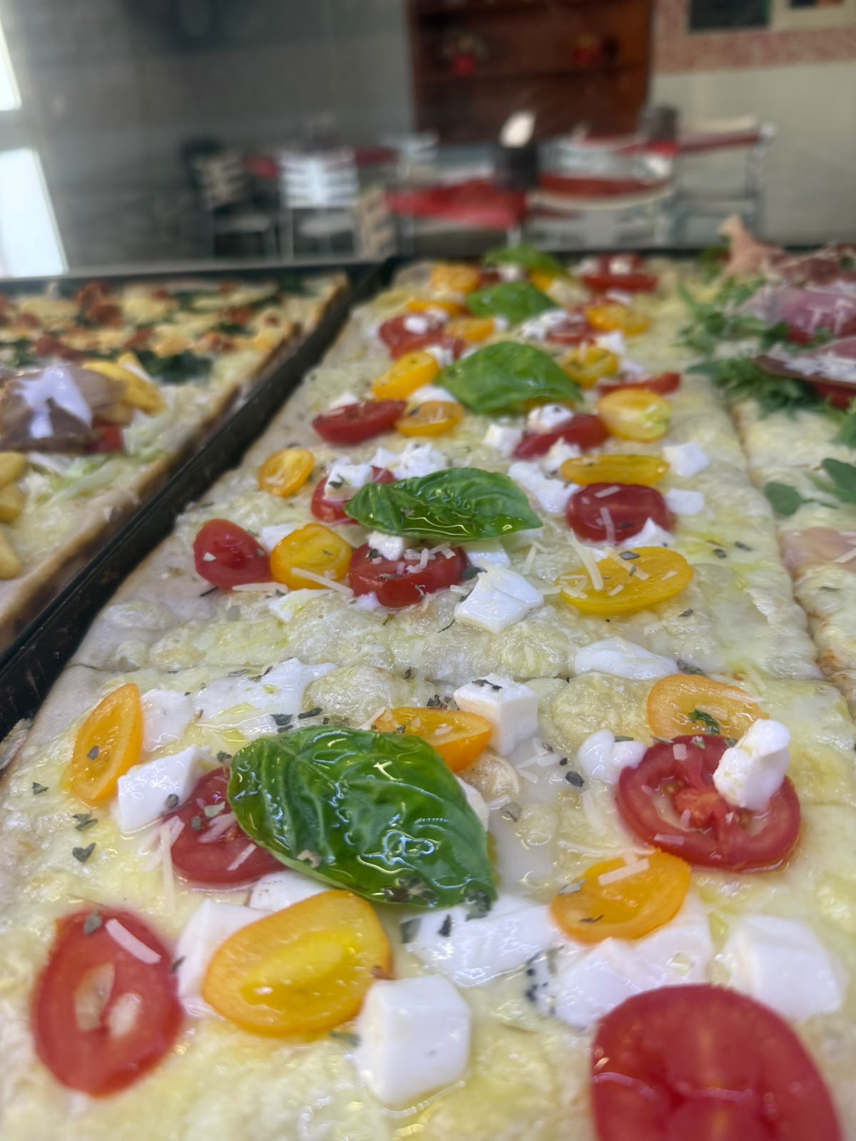 Pizza al taglio con pomodorini, basilico e mozzarella